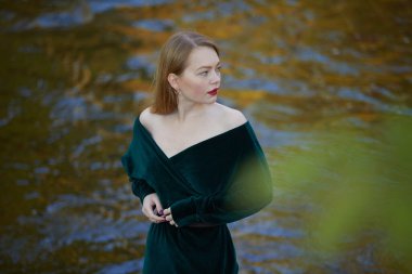 Kırmızı dudaklı zarif kadın nehirde poz veriyor.