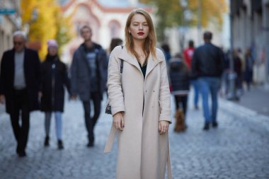 Kırmızı dudaklı, paltolu moda kadını sokakta poz veriyor. 