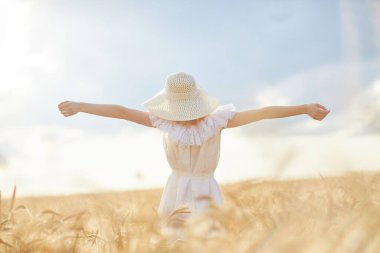 Buğday tarlasında gündüz poz veren şapkalı beyaz kadın.