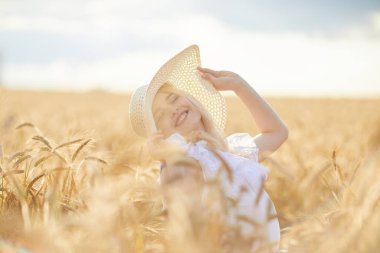 Şapkalı mutlu kadın portresi, buğday tarlasında poz veriyor. 