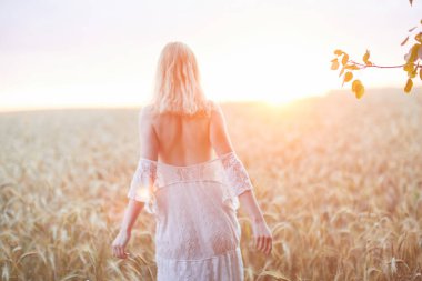 Şapkalı beyaz kadının buğday tarlasında gündüz poz verişi.