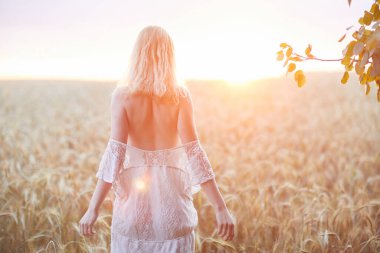 Şapkalı beyaz kadının buğday tarlasında gündüz poz verişi.