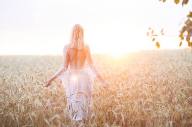 Şapkalı beyaz kadının buğday tarlasında gündüz poz verişi.