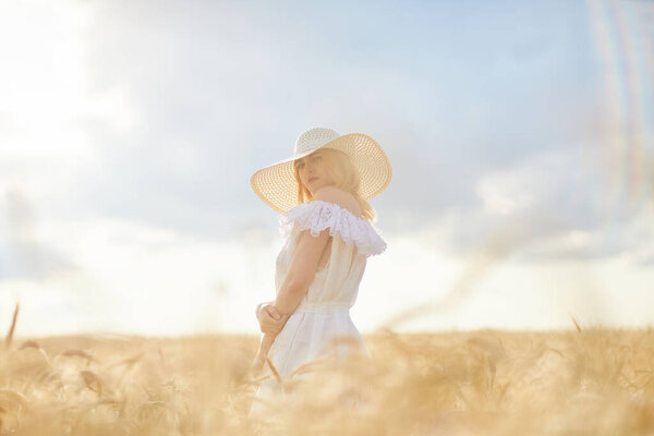 caucasian woman in hat posing in wheat field during daytime