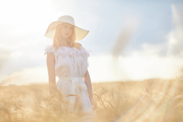 caucasian woman in hat posing in wheat field during daytime
