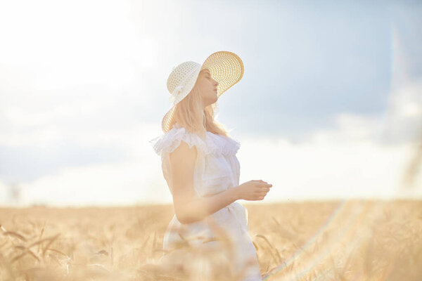 caucasian woman in hat posing in wheat field during daytime