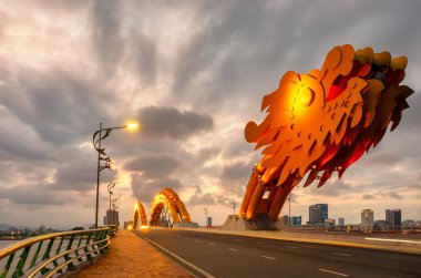 Danang Dragon bridge through Han river in Da Nang city in Vietnam. Dragon bridge at sunset which is a very famous destination for tourists clipart