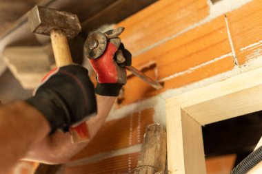 Duvarda kablo döşemek için delik açan bir adamın elleri.