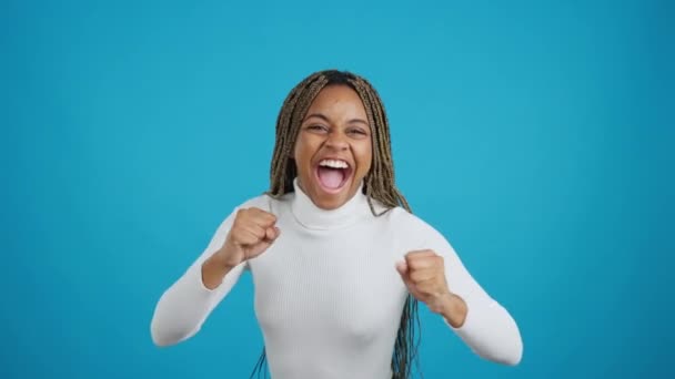 空気中の拳で祝うアフリカの女性の青の背景を持つビデオ — ストック動画