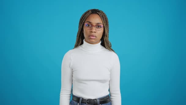 Film Niebieskim Tłem Afrykańskiej Kobiety Okularach Wpatrującej Się Kamerę Niedowierzaniem — Wideo stockowe
