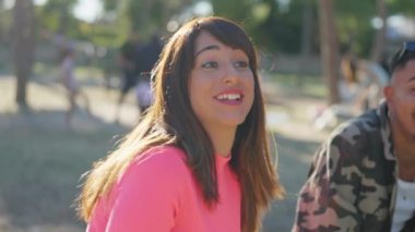 Güzel bir kadın parkta arkadaşlarıyla konuşuyor ve gülüyor.