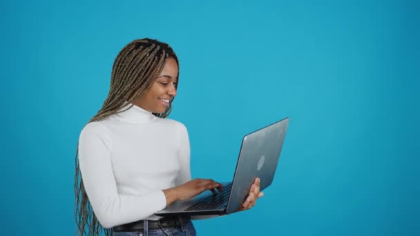 Video Blue Background Happy African Woman Standing While Using Laptop — Stockvideo