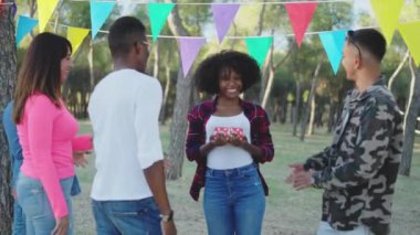 Group of multiethnic friends kissing while celebrating a birthday party in a park