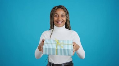 Video with blue background of an african woman smiling at the camera while giving a gift