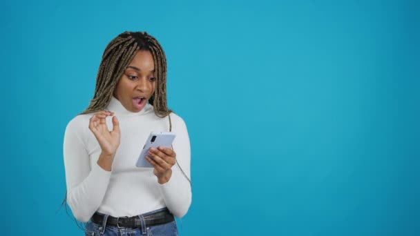 Video Blue Background African Woman Looking Mobile Phone Expression Surprise — Stockvideo