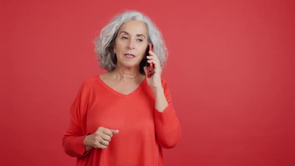 Студійне Відео Червоним Тлом Розлюченої Зрілої Жінки Говорить Мобільному Телефоні — стокове відео