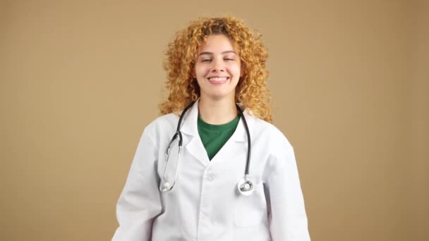 演播室录象 一位卷曲头发的年轻女医生交叉着双臂对着摄像机微笑 — 图库视频影像