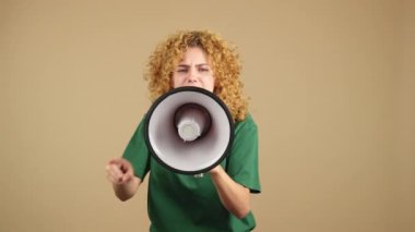 Studio video of a woman with curly hair looking at camera and shouting using a loudspeaker