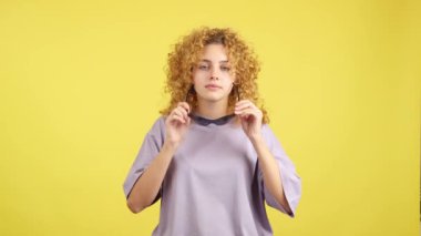Studio video with yellow background of a rude woman with curly hair and sunglasses