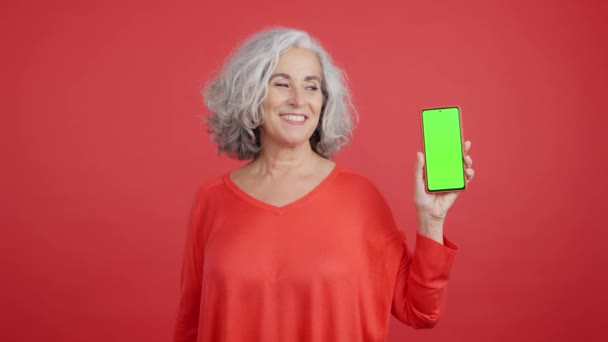 Студійне Відео Червоним Тлом Зрілої Жінки Показує Екран Хроми Мобільного — стокове відео
