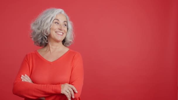 Студійне Відео Червоним Тлом Усміхненої Зрілої Жінки Вказує Бік — стокове відео