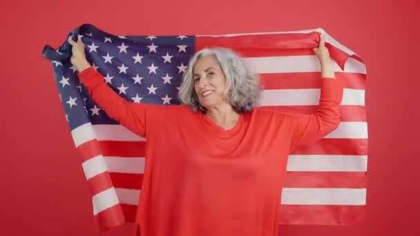 北米国旗を掲揚する幸せな熟女の赤い背景を持つスタジオビデオ — ストック動画