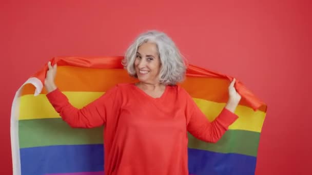 Студийное Видео Красным Фоном Зрелой Женщины Завернутой Радужным Флагом — стоковое видео