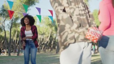 Nervous girl receiving anniversary gifts from friends in a park