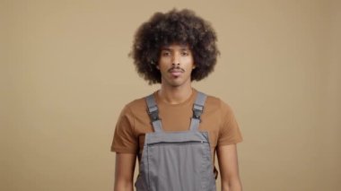 Serious african man carpentry worker looking at camera with the arms crossed in work uniformin studio