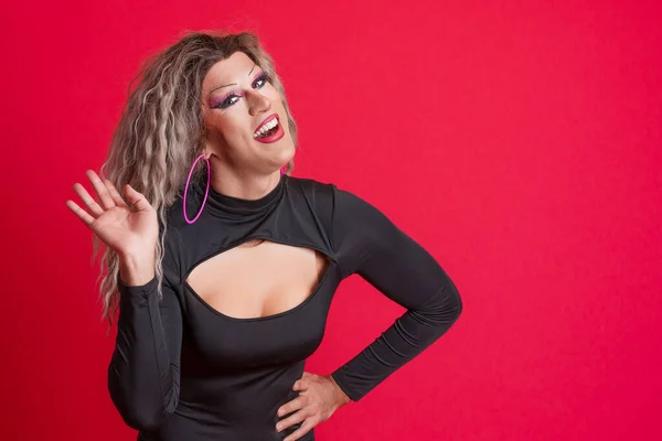Transgender person waving hand looking at camera. Red background