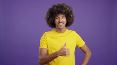 African man with curly hair gesturing agreement raising a thumb up in studio