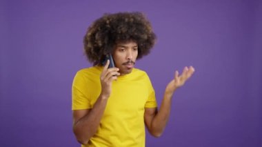Angry african man with curly hair talking to the mobile in studio