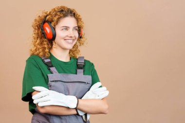 Studio image of a distracted woman carpentry worker with tools and work uniform
