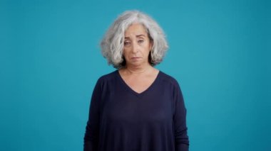 Studio video with copy space and blue background of a Sad mature woman about to cry