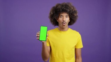 Stüdyoda krom ekranlı cep telefonu tutan sürpriz Afrikalı adam.