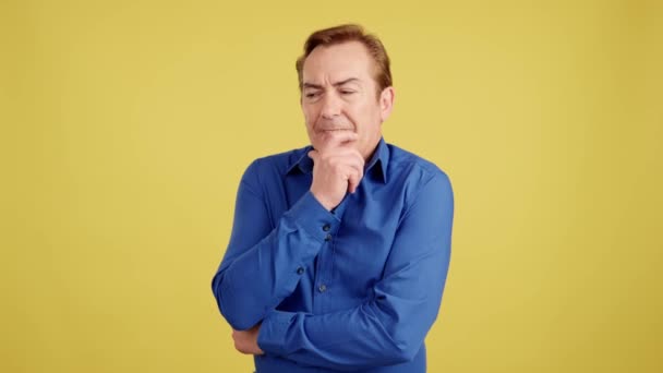 Mature Man Gesturing Pensive Forgetting Something Studio Yellow Background — Stockvideo