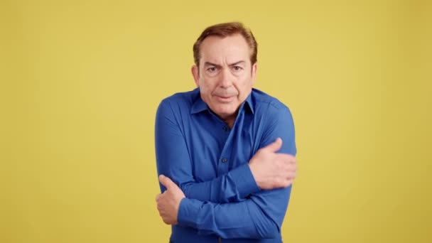 Mature Man Covering Arms Cold Studio Yellow Background — Vídeo de Stock