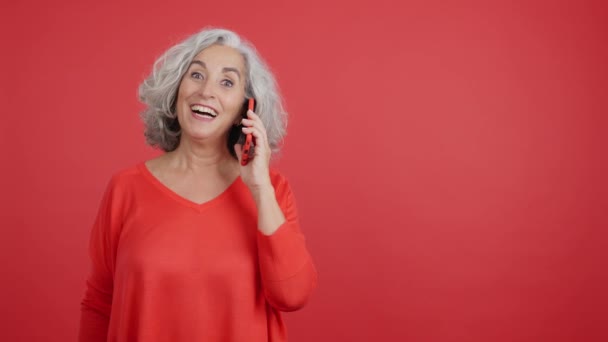 Студийное Видео Красным Фоном Удивленной Взрослой Женщины Разговаривающей Мобильным — стоковое видео