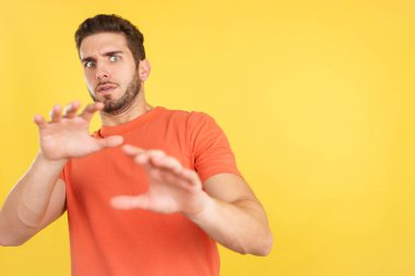 Caucasian man gesturing with the hands in fear in studio with yellow background