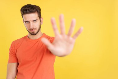 Caucasian man gesturing prohibition with hand in studio with yellow background