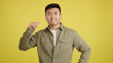 Shocked chinese man gesturing that he is forgetting something in studio with yellow background