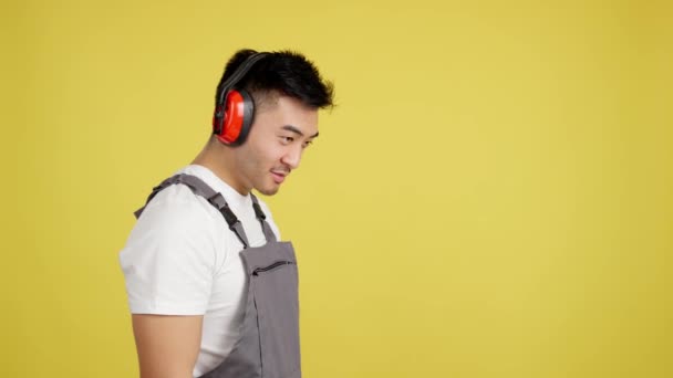 Stüdyoda Sarı Arka Planda Kameraya Gülümseyen Koruyucu Teçhizatlı Çinli Marangoz — Stok video