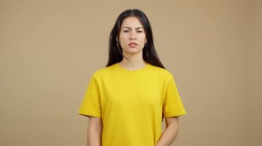 Hispanic woman crossing the arms with an angry expression in studio with brown background