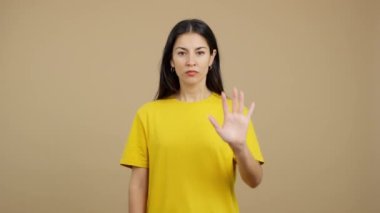 Caucasian woman gesturing prohibition with hand in studio with brown background