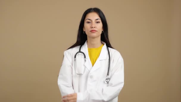 深刻なパニック女性医師見ますザ カメラとともに腕交差でスタジオとともに茶色の背景 — ストック動画