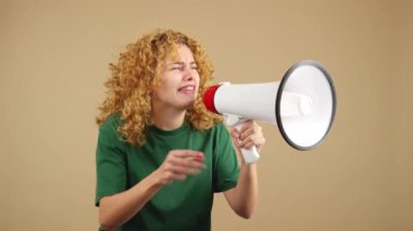 Studio video of an upset woman with curly hair shouting using a loudspeaker