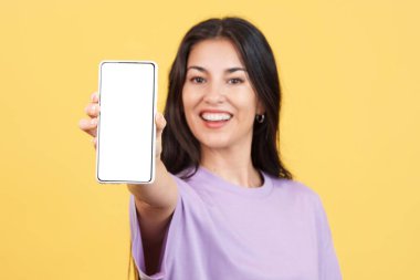 Blank screen of the mobile held by a caucasian woman in studio with yellow background