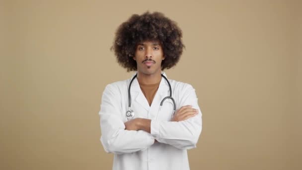 Серйозний Африканський Лікар Кучерявим Волоссям Стоїть Дивиться Камеру Руками Схрещеними — стокове відео
