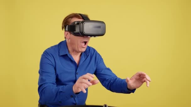 带有黄色背景的演播室视频 一个成熟男子在使用虚拟现实护目镜时做手势 — 图库视频影像