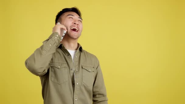 Happy Chinese Man Talking Mobile Studio Yellow Background — ストック動画